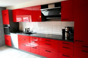 una cucina rossa con banconi neri e armadi rossi di Berga Farmhouse a Berga