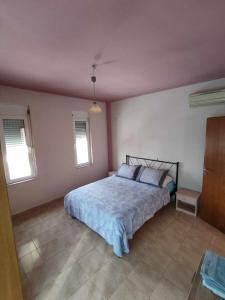 een slaapkamer met een bed en 2 ramen bij Dinos Pool Apartment in Kardamaina
