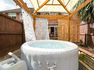 a hot tub in a backyard with a pergola at Luxury 2-bedroom Townhouse in Central Canterbury with Hot Tub, Garden & Private Parking! in Canterbury
