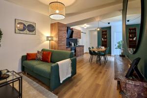 uma sala de estar com um sofá verde e uma sala de jantar em Le Oliva chez les M by Primo Conciergerie em Nevers