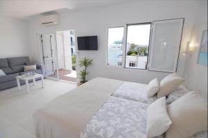 a white bedroom with a large bed and a couch at Apartamentos Casa Franziska in Talamanca