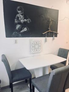 a white table and chairs with a picture on the wall at Lorand's Place near the River in Cluj-Napoca