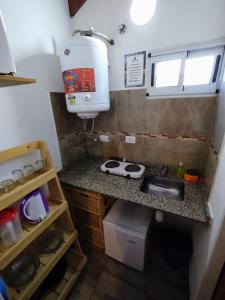 a small kitchen with a sink and a water tank at Las Marilubis Calamuchita in Santa Rosa de Calamuchita