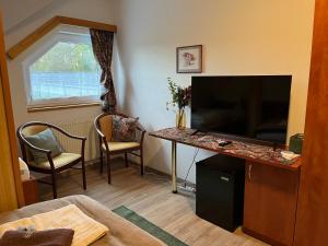 uma sala de estar com televisão e uma mesa com cadeiras em Restaurace Staré Sedlo em Orlík