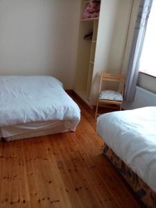 1 dormitorio con 2 camas, silla y ventana en Atlantic View, en Doonbeg