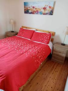 a bedroom with a red bed with red sheets and pillows at Atlantic View in Doonbeg