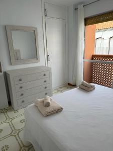een slaapkamer met een bed en een dressoir met handdoeken erop bij Calabardina Playa 2 con Wifi in Calabardina