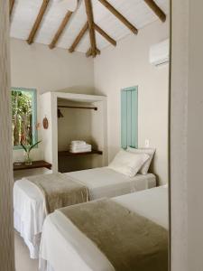 two beds in a room with white walls at Pousada Refazenda in Corumbau +57 photos