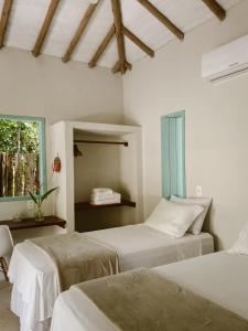 a bedroom with two beds and a window at Pousada Refazenda in Corumbau