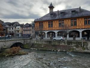 un bâtiment à côté d'une rivière avec un pont dans l'établissement Studio cosy classé 3 étoiles dans cœur historique, à Arreau