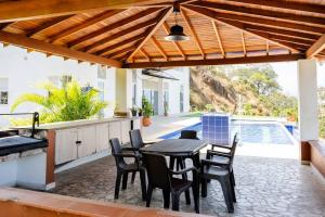 a patio with a table and chairs under a wooden pergola at Finca Rosa Linda Stunning Views Jacuzzi Pool in Sopetrán