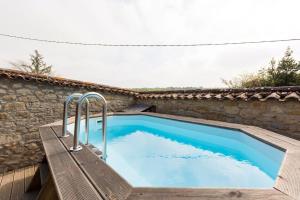 a swimming pool with a bench next to a stone wall at Escale à Pelagrua in Pellegrue