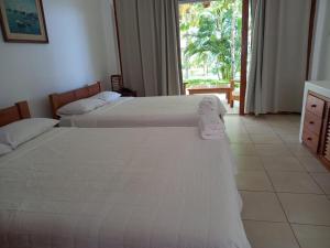 two beds in a hotel room with a window at Bungalows & Suites Punta Camarón in Zorritos