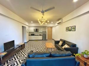 カンドリムにあるLuxury Apartment w infinity pool nr Candolim beachの青いソファとキッチンのあるリビングルーム