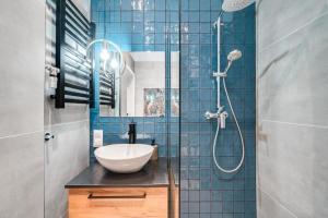 ein blau gefliestes Bad mit einem Waschbecken und einer Dusche in der Unterkunft PAPUGA Apartment ~ 700m Main Square ~ Self check-in 24h in Breslau