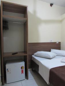 ein Schlafzimmer mit 2 Betten und einem Bücherregal in der Unterkunft Hotel Biz a 8 minutos do Brás, a 15 minutos da 25 de março e a 8 minutos do Bom retiro in São Paulo