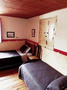 Un dormitorio con 2 camas y una silla. en Hostal Restaurante La Gata Carola, en Salento