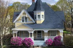 una casa amarilla con flores rosas delante en Beech Street Retreat, en Rockland