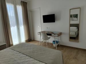 una camera con letto, scrivania e specchio di Le Nereidi Green Resort Elisa a Sirolo