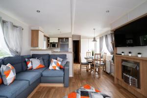 a living room with a blue couch and a kitchen at Mendip Close in Burnham on Sea