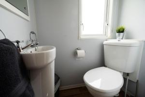Mendip Close في بورنهام اون سي: حمام ابيض مع مرحاض ومغسلة