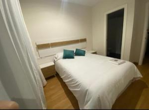 a bedroom with a white bed with two blue pillows at Balcón del atardecer in Barbate