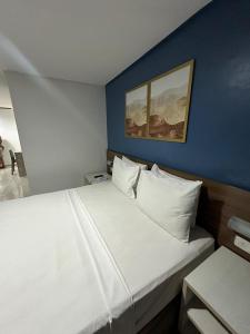 a bedroom with a large white bed with a blue wall at Imperial Tambau By Loui in João Pessoa