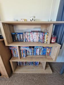 uma estante de livros de madeira cheia de DVDs em B17 Sunnymede Caravan Park, Fantasy Island, Ingoldmells em Ingoldmells