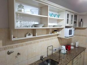una cucina con mobili bianchi, un lavello e un microonde di Alto Ramon a Neuquén