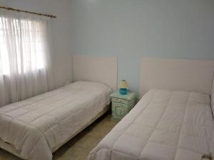 2 letti in una camera da letto con tavolo e finestra di Alto Ramon a Neuquén Altre 2 foto