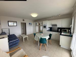 een keuken en een woonkamer met een tafel en een blauwe bank bij Studio en résidence face mer avec parking in Le Touquet-Paris-Plage