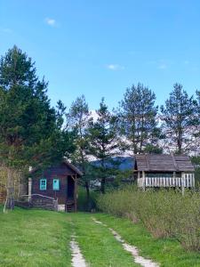 塞拉耶佛的住宿－Cottages of Nišići，田野中的一座小房子和一座建筑物