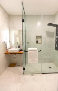 uma casa de banho com uma cabina de duche em vidro e um lavatório. em Xhale Azores em Angra do Heroísmo
