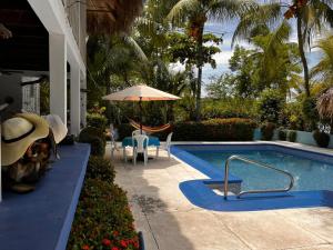 a swimming pool with a table and chairs and an umbrella at Casa Aris in Escuintla