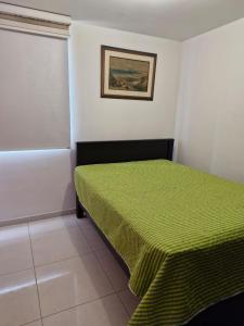 1 dormitorio con 1 cama con colcha verde en Apartamento en conjunto con piscina, en Ibagué