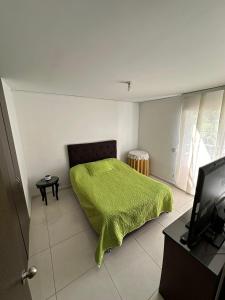 1 dormitorio con 1 cama verde y TV en Apartamento en conjunto con piscina, en Ibagué
