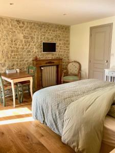 a bedroom with a bed and a table and a tv at La Chambre du Saule in Trévières