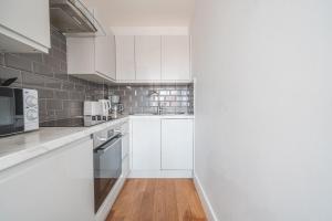 een witte keuken met witte kasten en apparaten bij Modern 1 Bedroom Apartment in Central Eastleigh in Eastleigh