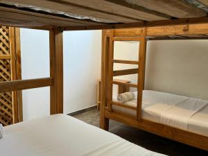 two bunk beds in a room with white sheets at Merakai Hostel Rincon del Mar in Rincón