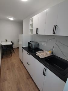 eine Küche mit weißen Schränken, einer Spüle und einem Tisch in der Unterkunft Apartma David in Most na Soči