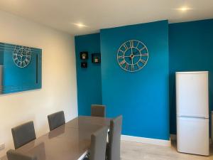 a dining room with a table and a clock on the wall at The Sailsbury Snug in Southend-on-Sea