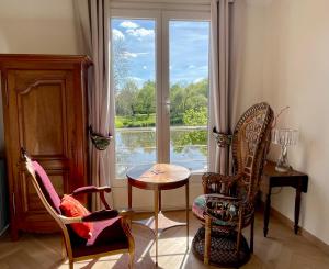 a room with two chairs and a table and a window at Le Moulin de Bury, Maison de campagne au bord de la rivière à 13 kms au Sud de Rennes in Chavagne