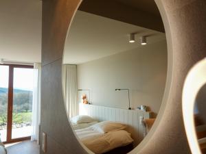 Schlafzimmer mit einem Bett und einem runden Spiegel in der Unterkunft Villa La Verdoyante in Lierneux