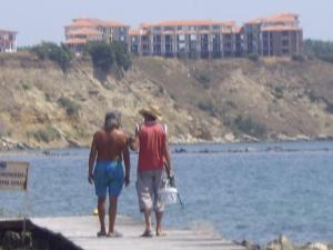 two people walking on a dock near the water at Studio Marina Cape 89 in Aheloy