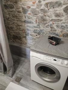 - un lave-linge blanc dans une pièce dotée d'un mur en pierre dans l'établissement Light and sea 2, à Kavala