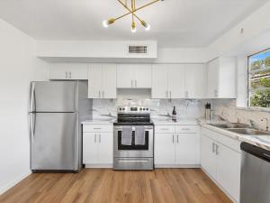 uma cozinha com armários brancos e um frigorífico de aço inoxidável em 3BR Newly Renovated In Miami 15 Min To Beach em Miami