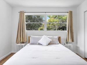uma cama branca num quarto com uma grande janela em 3BR Newly Renovated In Miami 15 Min To Beach em Miami