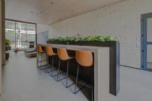 a lobby with a counter with chairs and plants at Roomo Transamerica SP Brooklin Santo Amaro in Sao Paulo