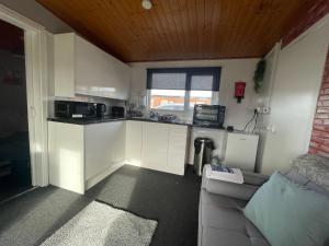 a kitchen with white cabinets and a couch in a room at Holiday Chalet in Mablethorpe