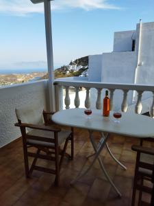 a table with two glasses of wine on a balcony at ANATOLI ROOMS SERIFOs in Serifos Chora